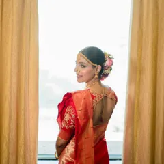 A beautiful back profile of my Maharashtrian bride, showcasing a traditional bun decorated with a mix of pink and white flowers, perfectly complementing her red saree.