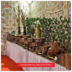 A traditional and grand buffet setup for a wedding reception. The arrangement features elegant copper and brass serving dishes on a beautifully decorated table, perfect for large celebrations.