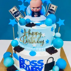 A fun two-tier Boss Baby theme cake. Decorated in shades of blue with stars, edible money, and the Boss Baby himself, this cake is perfect for a little one who rules the house.