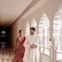 The groom waits with a gentle smile as his bride approaches through a sunlit palace corridor. This candid first look moment is filled with anticipation and the timeless beauty of royal architecture.