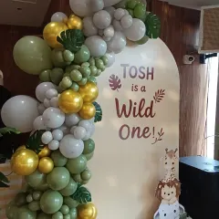 A wider angle of the 'Tosh is a Wild One' setup. The organic balloon garland beautifully frames the custom backdrop, creating a perfect spot for birthday photos.
