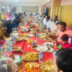 A candid shot of guests enjoying a traditional meal at a 'dawat' in Chitradurga. You can see large platters of biryani being shared, which is the heart of these communal feasts.