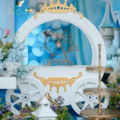A close-up of the Cinderella-inspired carriage prop. This piece served as a beautiful dessert stand and a central element of the fairytale decor, detailed with elegant white and gold accents.