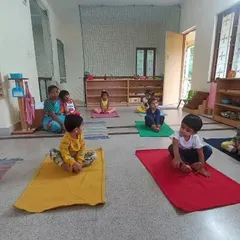 Children sitting peacefully on their mats at the start of a yoga session in our Montessori classroom.