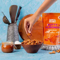 A simple, clean shot featuring a hand model picking up a nutty almond. This style of photography helps customers visualize themselves enjoying the product, making it more relatable.