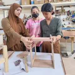 Students assembling a small piece of furniture. This hands-on experience is invaluable for understanding how designs translate into real-world objects.