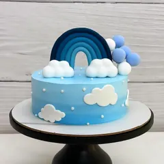 A beautiful blue ombre cream cake with a rainbow and fluffy fondant clouds. It feels like a perfect slice of a clear winter sky.