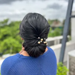 A clean, classic low bun with a simple twist detail, adorned with elegant pearl and gold pins. This timeless style is a must-know for any hairstylist.