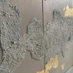 A close-up showing the contrast between the rough, grey texture and the smooth, shimmering gold leaf. This combination creates a stunning visual and tactile experience.