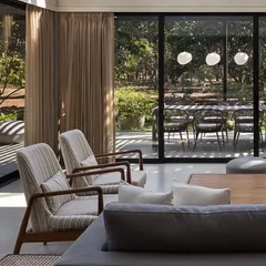 The living room's glass walls slide open to seamlessly connect with the outdoor dining terrace. This design choice erases the line between indoors and out, allowing for a fluid living experience that embraces the natural surroundings.