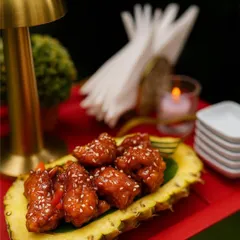 Bold Korean flavors plated with creativity. This dish features crispy chicken coated in a sweet and spicy gochujang sauce, served in a hollowed-out pineapple for a presentation that is both rustic and chic.