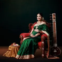 A regal portrait of a mom-to-be in a green silk saree, seated in an ornate chair with a sitar, creating a classical and artistic composition.