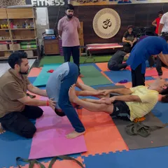 Here, I am assisting a student in a deep forward bend during a partner yoga session. This kind of support helps release the lower back and hamstrings safely.