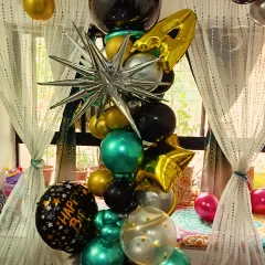 A stylish and modern balloon bouquet perfect for a birthday surprise. This arrangement includes chrome balloons in green and silver, star-shaped foil balloons, and a 'Happy Birthday' balloon.