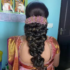 A beautiful and intricate braid with a voluminous, textured finish, adorned with a pink floral accessory. This is an advanced style that is perfect for a modern bride.