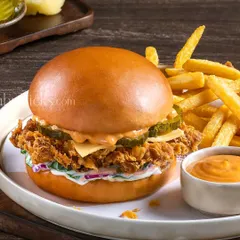 A crispy fried chicken burger with coleslaw and spicy sauce, served with a side of golden fries for a complete meal shot.