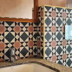 This bathroom features bold, geometric cement tiles in a striking color combination. The simple chrome fixtures and granite countertop allow the tilework to be the main focus of the design.
