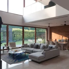 A home should be filled with light and life. This double-height living space, opening directly onto a green lawn, illustrates how we choreograph spatial volumes to create bright, airy interiors that connect seamlessly with the outdoors.