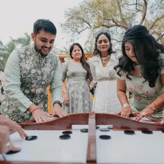 Guests enjoying a game of tabletop carrom at an outdoor carnival. I organize fun, interactive games and activities to act as icebreakers and keep everyone entertained.