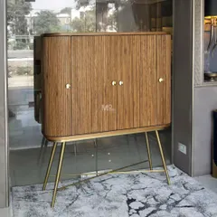 The Ibis bar cabinet blends a rich brown wood finish with sleek metal legs for a timeless appeal. Its fluted doors and curved silhouette make it a standout piece for any contemporary entertainment space.
