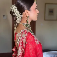 This side profile showcases a sleek bridal bun adorned with a full gajra of baby's breath. The clean lines and classic floral choice make it a timeless option for any traditional wedding ceremony.
