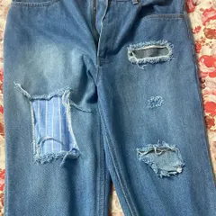 Custom ripped and repaired jeans. This pair features distressed areas and unique patches, including a striped fabric insert, for a personalized, worn-in style.