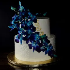 This two-tier red velvet cake is one of my favorites. The deep blue orchids cascading down the side create a dramatic and elegant look, complemented by delicate gold leaf accents and textured buttercream for a classy finish.