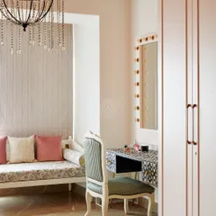 A dedicated vanity area within the walk-in closet, complete with a mirror surrounded by classic Hollywood-style bulbs. A comfortable seating nook by the window provides a perfect spot to relax.