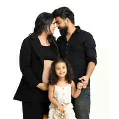 A heartwarming studio family portrait with parents and their young daughter, who is holding a pair of tiny baby shoes. Including older siblings is a wonderful way to capture this special time for the whole family.