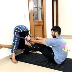 To enhance flexibility and achieve challenging poses, I sometimes incorporate tools like a yoga strap. Here, the strap provides the necessary leverage to help my client deepen their forward bend safely, bringing them closer to the full expression of the pose. This demonstrates how we can work together to overcome physical limitations.