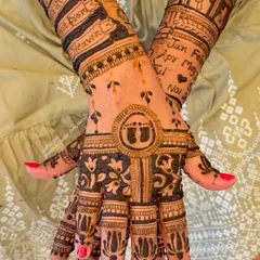 The back of the hands for a baby shower mehendi, featuring tiny baby feet inside a circle and delicate floral patterns. A sweet and meaningful design.