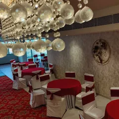 This banquet hall was styled with a classic red and white theme. The setup includes round table dining with matching chair covers and a patterned carpet runner to welcome guests.