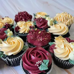 A set of custom floral cupcakes designed for an elegant event. I used a rich burgundy and soft yellow buttercream to pipe different styles of flowers, finished with sugar pearls and edible gold leaf for a touch of luxury.