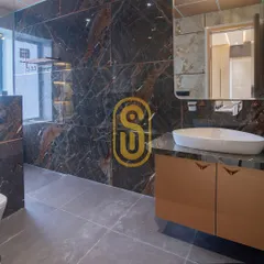 This bathroom features a bold combination of dark marble with striking veins and a modern vessel sink. The custom vanity provides storage, and the large mirror enhances the sense of space.