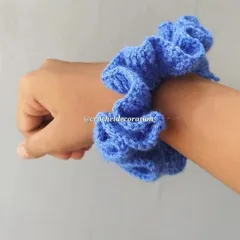 The crochet scrunchie worn on a wrist. It's a stylish and comfortable accessory, available in a variety of colors to match your outfit.