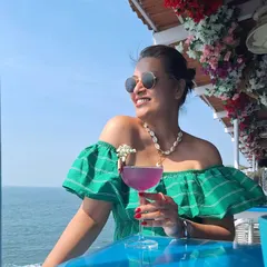 Enjoying a cocktail by the sea in Goa. This off-the-shoulder green striped dress is perfect for a beachside bar, paired with a shell necklace to complete the tropical vibe.