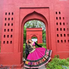 A full-length shot showcasing the beautiful flare of the Navratri ghagra against a vibrant red backdrop. This look is all about celebrating with color and style.