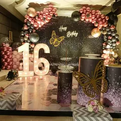 A chic and trendy 'Sweet 16' party with a black shimmer wall, rose gold balloons, and butterfly accents for a modern look.