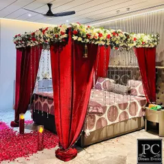 This view highlights the full effect of the romantic bedroom decor. The combination of red velvet, fresh flowers, and soft lighting creates a truly special and memorable ambiance for the couple.