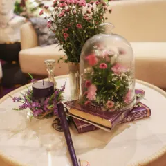 A moment frozen in time. A delicate floral arrangement captured under a glass cloche, placed on vintage books with a deep purple candle. It's these small, romantic vignettes that add soul to a space.