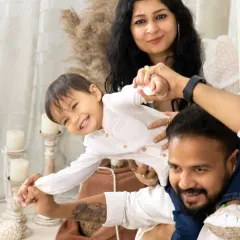 A fun and energetic shot of a little boy enjoying a shoulder ride with his dad, while his mom holds on, all laughing together.