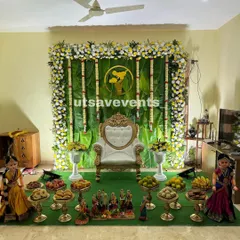 For a more natural and serene theme, I create backdrops using fresh banana leaves. This setup, perfect for an intimate baby shower at home, features hanging jasmine garlands and a classic white and gold throne, complemented by a full arrangement of ceremonial plates.