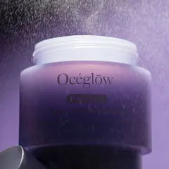 An atmospheric shot of an Océeglow jar with a fine mist spraying over it. The purple tones and dramatic lighting create a mysterious and magical feel, suggesting the product has transformative qualities. This is a great example of using elements to tell a product's story.