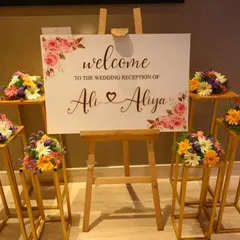 We create personalized welcome signs to greet your guests. This elegant wedding reception sign is displayed on an easel and surrounded by beautiful, fresh flower arrangements.