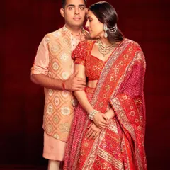 A beautiful couple's look featuring a stunning red Abu Jani Sandeep Khosla lehenga. The intricate detailing and rich color palette make it a perfect choice for a wedding celebration.