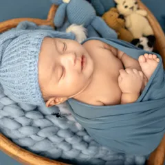 Tucked into a cozy blue wrap, this little one is dreaming peacefully. I use gentle wrapping techniques to keep babies comfortable and secure during their first photoshoot.