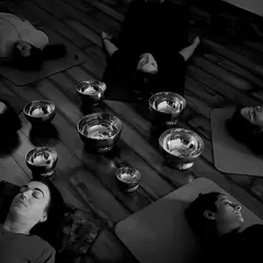 A moment of deep rest during a sound healing session. Students lie in Savasana while the vibrations of the Tibetan singing bowls wash over them, creating a meditative state that facilitates healing on a cellular level.