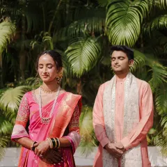A serene moment as the Marathi bride and groom stand with their eyes closed, perhaps in prayer or quiet contemplation before a ritual. The lush green background adds to the tranquility of the scene.