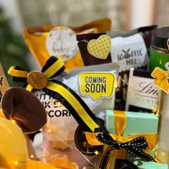 A peek at the goodies inside, including gourmet popcorn, Lindt chocolates, and other treats for the mom-to-be, all tied together with the yellow and black bee theme.