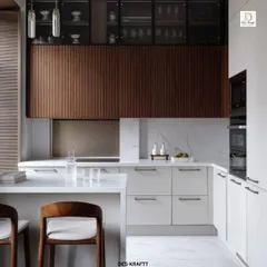 This modern kitchen design balances textures beautifully, with vertically fluted wood upper cabinets, sleek white lower cabinets, and a clean white countertop that extends into a breakfast bar.